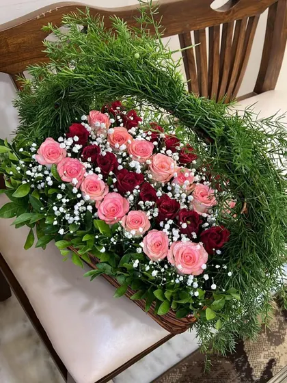 A side view of the fresh rose basket, showcasing the lush greenery that forms the handle and the full, healthy blooms that make this arrangement so special.