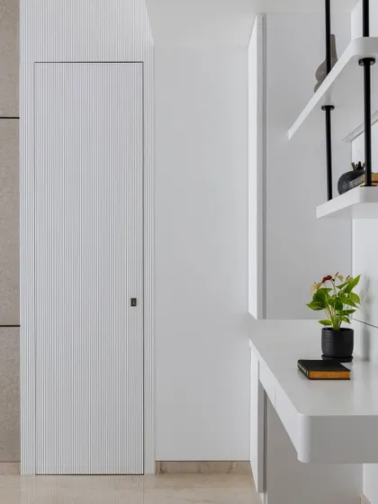 A modern bedroom featuring a striking lavender PU paint bed backdrop with MDF paneling. A hidden door within the paneling leads to an attached walk-in wardrobe, seamlessly blending style and convenience.