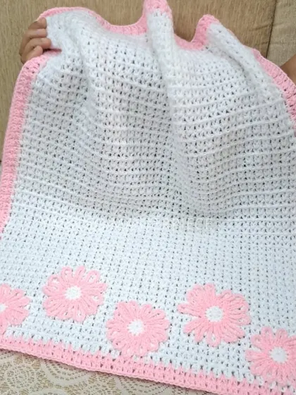 A classic color combination, this baby blanket is white with a soft pink border and features five matching pink daisy flowers.