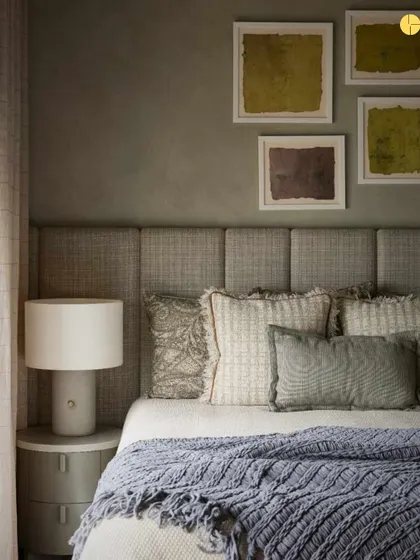 A close-up of the guest bedroom's styling. The combination of different pillow textures, a knitted throw, and abstract art against a textured wall showcases our attention to detail in creating layered, tactile interiors.