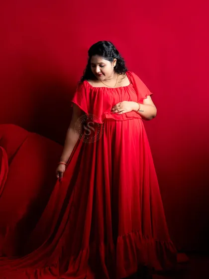 The vibrant red gown stands out beautifully against the matching red backdrop in our studio. This is a powerful and confident solo maternity portrait.