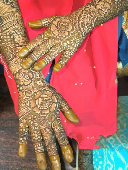 A detailed bridal design with the fingertips covered in henna, ready to leave a deep, dark stain.