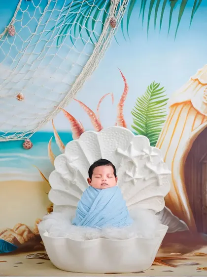 An imaginative under-the-sea theme, with the baby nestled in a giant clamshell prop against a beach backdrop.