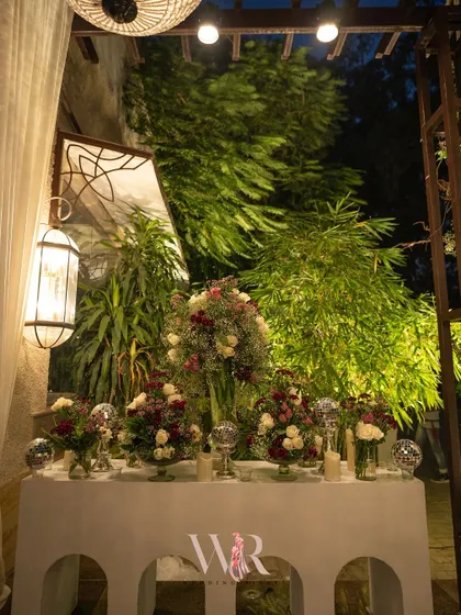 A floral console at the entrance, featuring arrangements of white and deep red roses, accented with sparkling disco balls for a touch of modern fun.