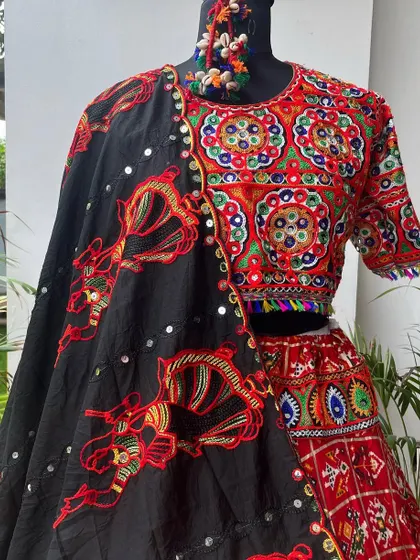 A mannequin shot of a black and red chaniya choli, showing the intricate elephant embroidery on the dupatta and the detailed mirror work on the blouse.