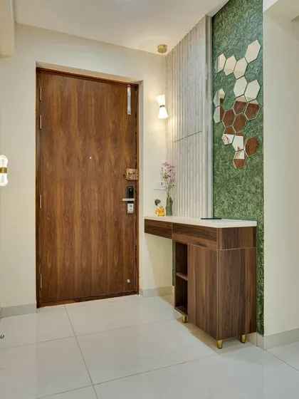 A console table at the entrance with a hexagonal mirror feature wall, combining wood, marble, and a pop of green for a stylish first impression.