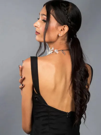 A profile shot that highlights the model's features and the elegant braided ponytail hairstyle. This angle is great for showing off the back of a garment or a hairstyle.