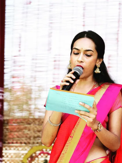 Focused and ready, reading my notes before an announcement. This was for a traditional South Indian event where I hosted in a classic pink and red saree, ensuring the program ran smoothly.