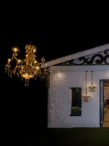 An architectural shot of the wedding venue at night, with the grand chandelier creating a stunning visual contrast.