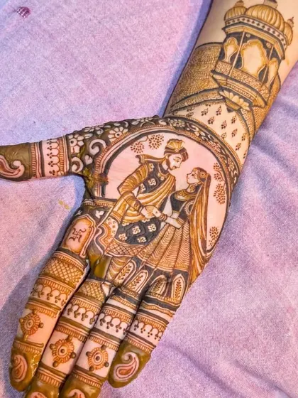 A close-up of a beautifully executed couple portrait on the palm. The groom is lovingly looking at the bride, with a royal jharokha design on the wrist.