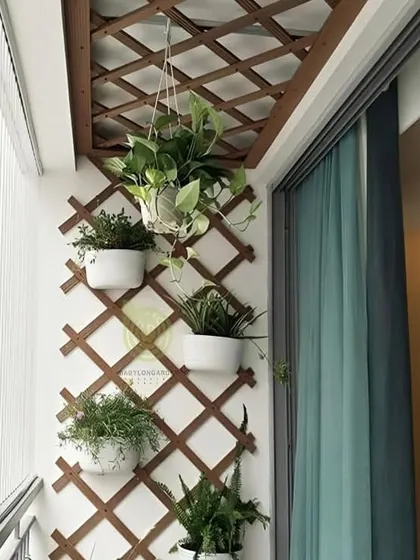 A simple yet effective way to add greenery and privacy is with a wooden lattice trellis. Here, we've used it as a framework for wall-mounted and hanging planters, creating a multi-level garden in a compact balcony.