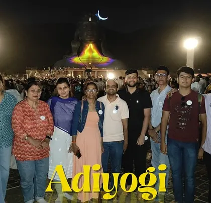 The group gathered for a photo in front of the Adiyogi statue at night, illuminated by colorful lights.