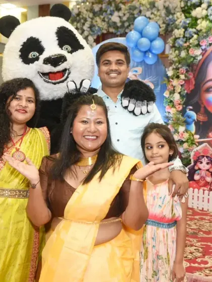 A family poses for a group photo with the panda mascot in front of the party backdrop.