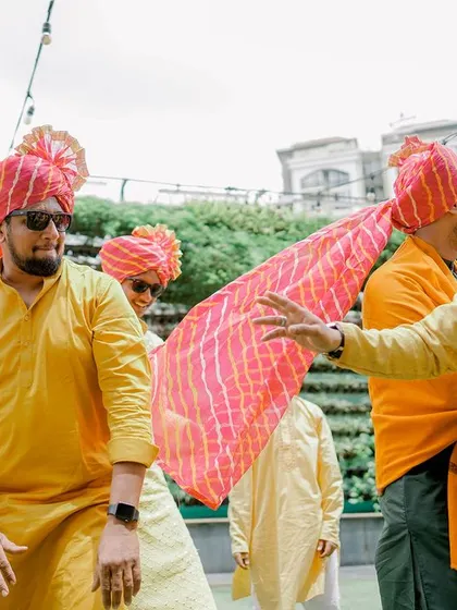 The men of the family, dressed in vibrant yellow and festive turbans, dance with joy during the Haldi celebrations.