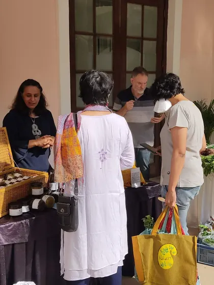 Customers interacting with a vendor selling homemade preserves.