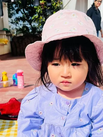 This child is ready for the sun in her wide-brimmed hat, learning about sun safety and seasons.