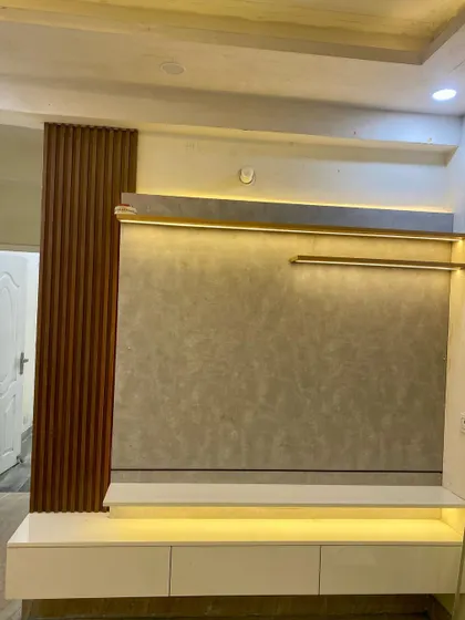 A simple and effective TV unit design. The combination of a textured back panel with wood fluting and a clean white console works well in any modern home.
