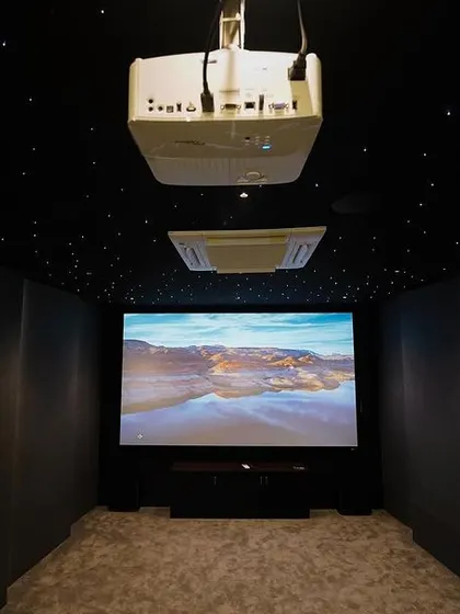 This head-on view from the back of the room shows the perfectly centered projector and the immersive scale of the 135-inch screen, ready to transport you into the movie.