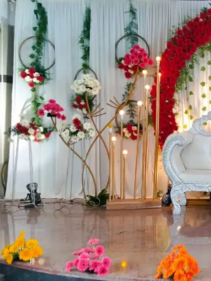 This is a classic wedding reception stage I designed. It features a grand floral arch with red roses, elegant white drapery, and warm lighting to create a romantic and timeless setting for the couple.