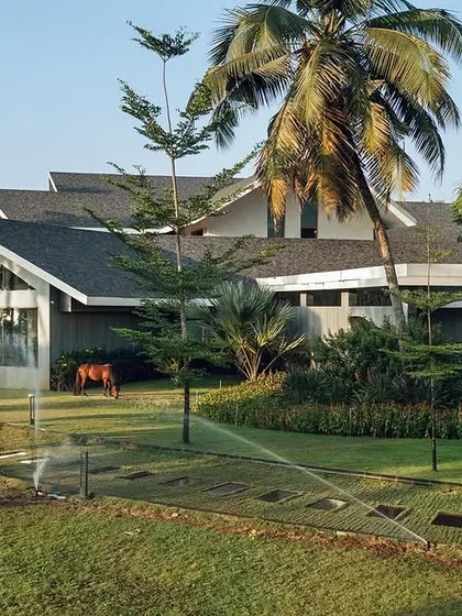 This Mangalore residence showcases a modern interpretation of traditional coastal architecture. The sloping roofs and large overhangs are designed for the tropical climate, while the manicured lawn with sprinklers adds to the resort-like feel.