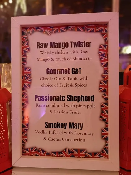 A custom-designed cocktail menu for the London-themed party. The menu features creatively named drinks like the 'Raw Mango Twister' and 'Passionate Shepherd', all framed with a Union Jack border.