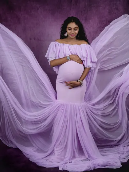 Angelic in lavender. The flowing fabric of this off-shoulder gown creates a beautiful wing-like effect, adding a touch of ethereal grace to this pregnancy photo.