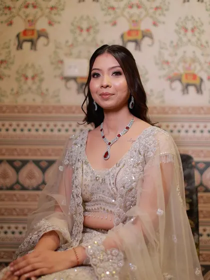 A portrait of the bride in her ivory gown. The soft shimmer on her eyes and glossy lips create a look of timeless charm.
