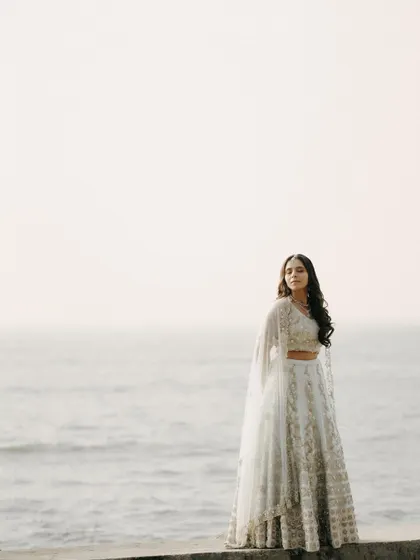 A beautiful solo portrait of the bride-to-be by the sea. Her elegant lehenga and the serene backdrop create a stunning image.