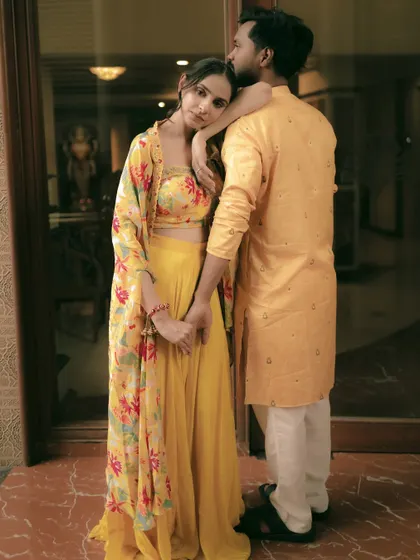 A full-length view of the couple's coordinated yellow floral outfits for their Haldi function.
