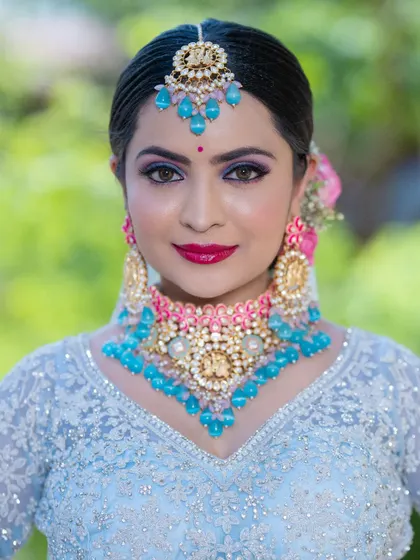 A direct portrait that captures the striking contrast between the cool blue outfit and the warm pink tones in the jewelry and makeup. The look is both modern and regal.
