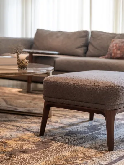 In this Palm Springs home, the design rests on restraint. Tactile upholstery on the sofa and a simple wooden ottoman create a feeling of quiet sophistication. The focus is on timeless materials and a calm color palette that supports a peaceful rhythm of living.
