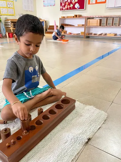 The Cylinder Blocks are a foundational sensorial material. By fitting each cylinder into its correct socket, the child refines their pincer grip for writing and develops their ability to visually discriminate between different dimensions.