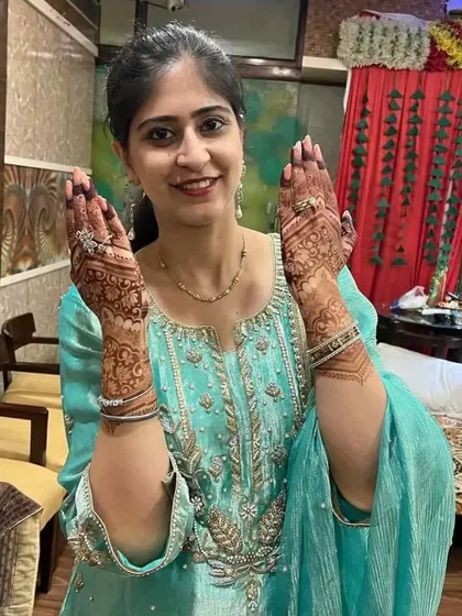 A happy client showing her festive mehndi for a party.