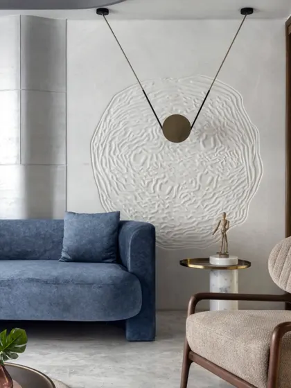 The interior of the Slender House embodies the 'less is more' philosophy. This textured wall art, paired with a minimalist pendant light, adds a layer of artistic expression to the clean, contemporary living space.