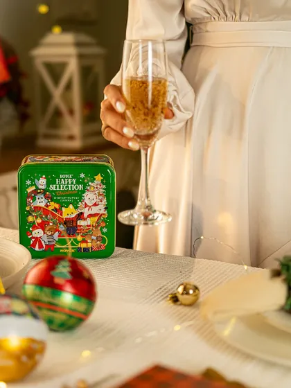 A lifestyle shot of a woman holding a glass of champagne next to a festive table setting featuring a Christmas-themed product.