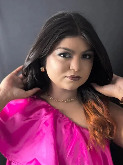 A student's work showcasing a bold look with a smokey eye and dip-dyed hair ends. The model wears a vibrant pink top, creating a fun and modern style.