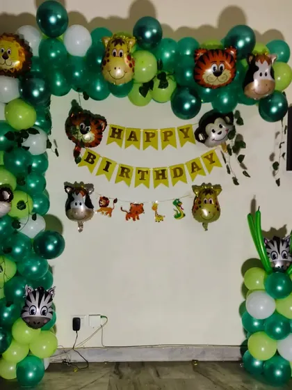 A simple yet fun jungle animal theme. The green balloon arch is decorated with multiple animal head foil balloons and a "Happy Birthday" banner.