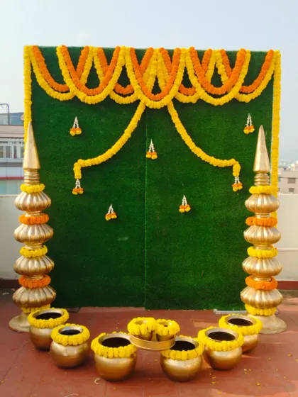 A simple and elegant Haldi backdrop with marigold garlands on a green background. This is a classic design that is always in demand for pre-wedding functions.