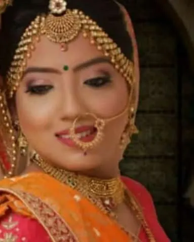 A close-up of a bride's face, showing the detailed eye makeup and the classic nose ring.