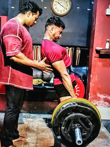 Perfect form is everything in a deadlift. I am personally guiding my student to ensure his back is set and his technique is flawless before he pulls. This hands-on correction prevents injury and builds true strength.