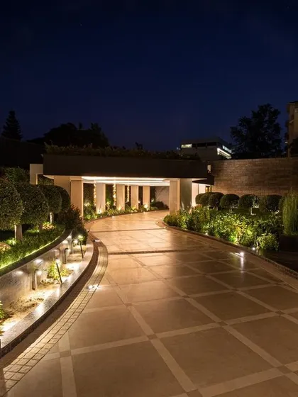 The entrance to a home sets the tone for everything within. Here, we designed a grand, illuminated driveway that is both welcoming and impressive, using a combination of ground lights, wall sconces, and accent lighting on the manicured shrubbery.