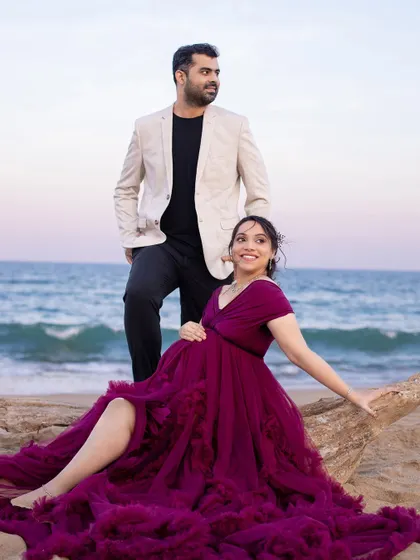 A stylish couple enjoying a relaxed moment on the beach. The flowing purple gown adds a pop of rich color to the serene landscape.