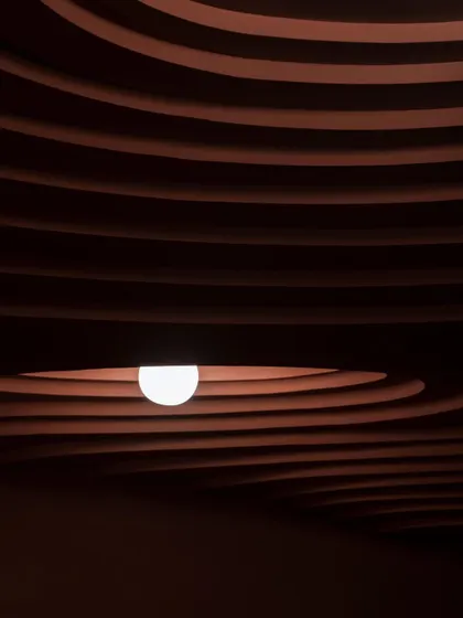 A detail from our award-winning 'Whispers in Motion' project. The dramatic, layered ceiling is sculpted to create a sense of rhythm and depth, with a single light source emerging like a pearl from within the form.