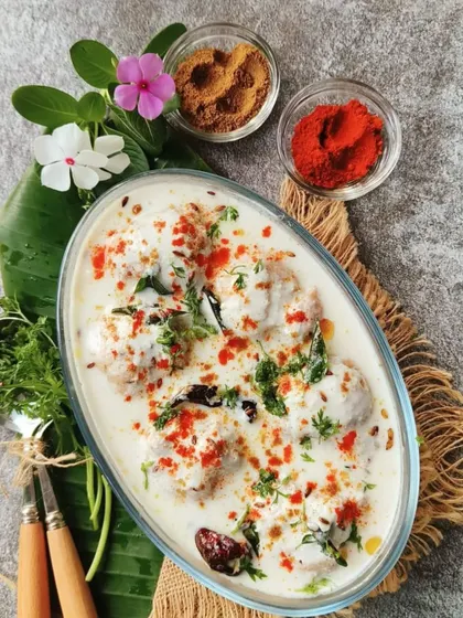 A refreshing bowl of Dahi Vada. These soft lentil fritters are soaked in creamy yogurt and garnished with spices and chutneys, a perfect dish for any celebration.