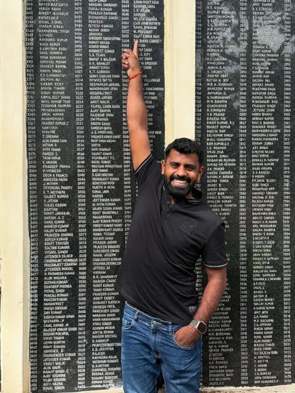 Pointing to my name on the monument at my school. A moment of immense pride and nostalgia.