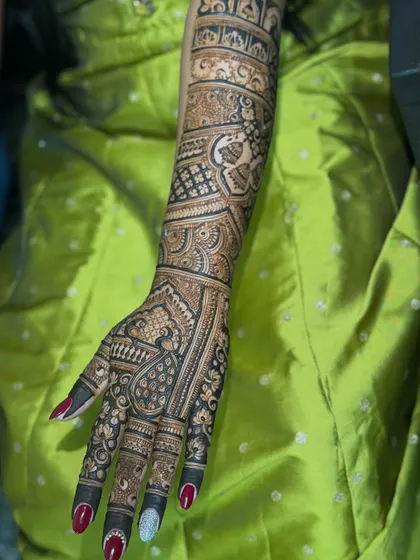 A full bridal arm demo against a vibrant background. This design is rich with traditional patterns, including paisleys and detailed grid work, showing the level of artistry we aim for.
