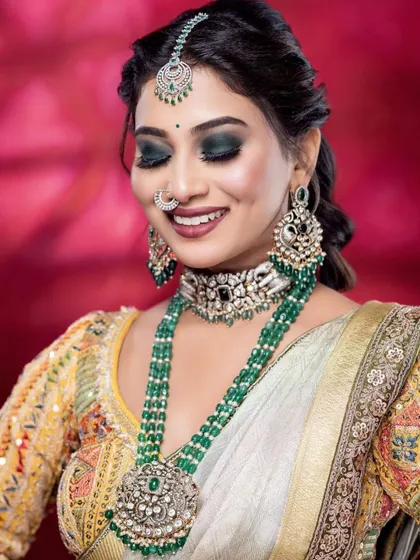 A happy, smiling shot that shows off the stunning emerald green jewelry and the intricate mirror work on the yellow blouse.