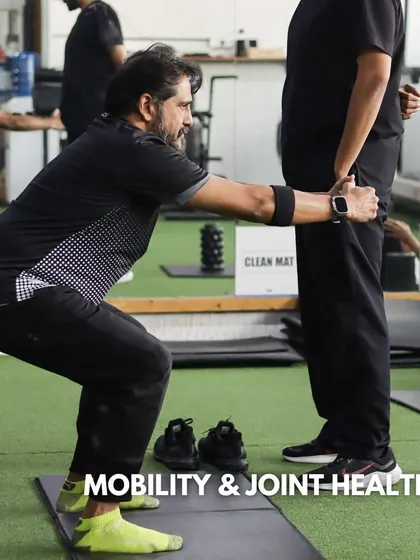 Mobility and joint health are crucial for pain-free movement. Here, a client works on squat mobility with a coach's assistance, ensuring his joints stay healthy and functional.