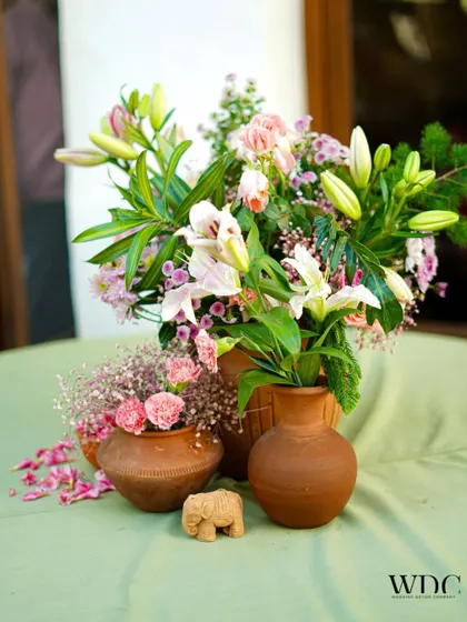 A close-up of the earthy and elegant centerpiece. The combination of terracotta, fresh lilies, and a tiny elephant figurine perfectly captures the theme's blend of rustic charm and tradition.