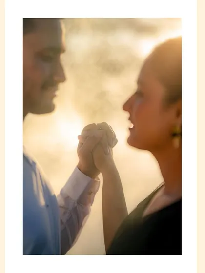 A close-up shot of a couple holding hands, silhouetted against a golden, hazy background. This artistic photo focuses on connection and intimacy.